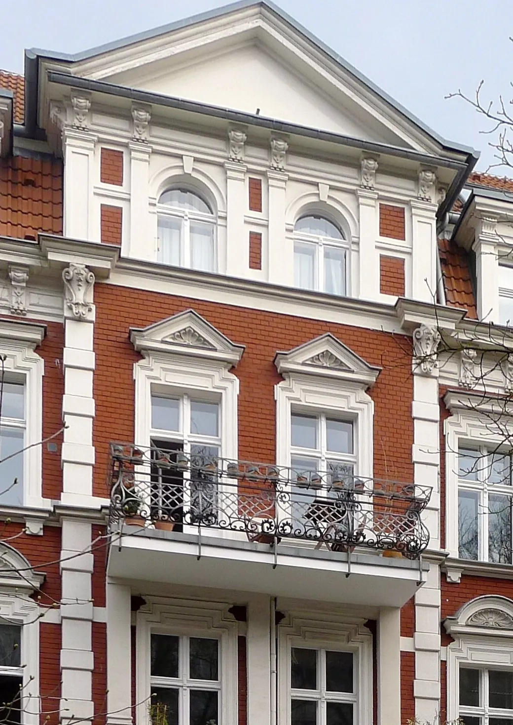 Ausschnitt einer Gründerzeitfassade mit Giebel, Stuck, Balkon und Klinker in Berlin